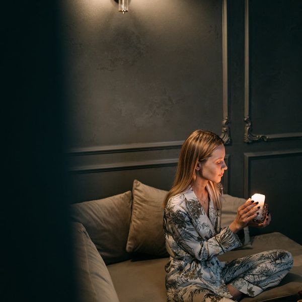 Woman stretching gently in a dimly lit room, suggesting evening calm.